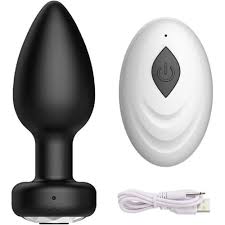 Black butt plug and white remote control with USB cable on a black background